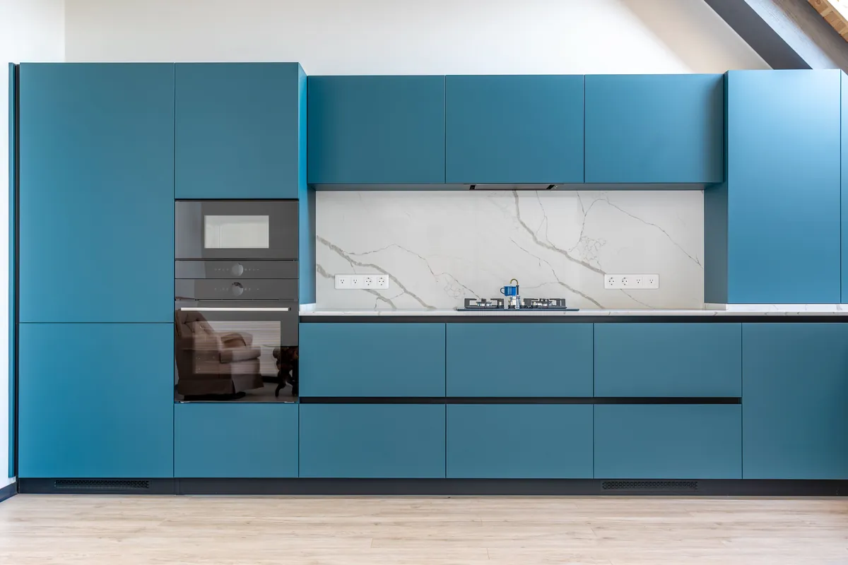 Cabinets refinished in a deep blue against a marble splashback.