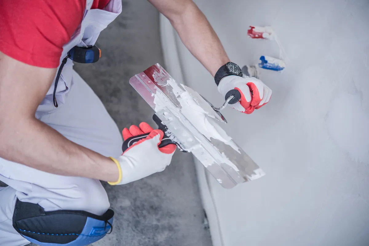 Drywall patch being filled and feathered out into the surrounding wall.