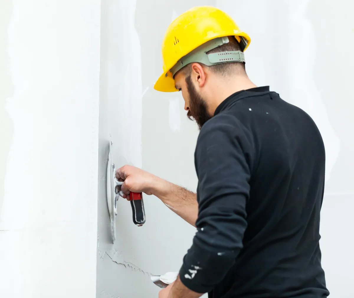 Joint compound being smoothed over a board seam with a taping knife.