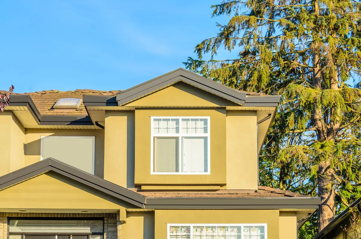 House exterior with freshly painted stucco, white window surrounds and a painted garage door.
