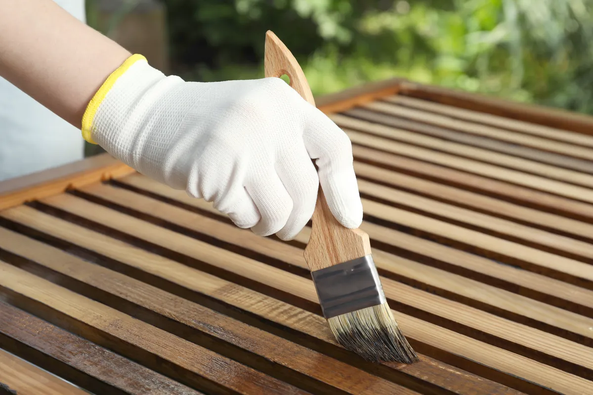 Stain being brushed along timber slats, working with the grain.
