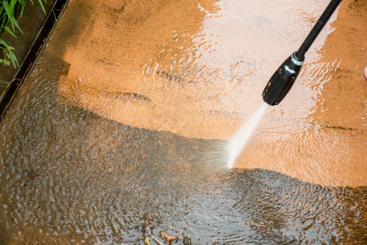 Concrete being cleaned with a high pressure jet, showing the line between washed and unwashed.