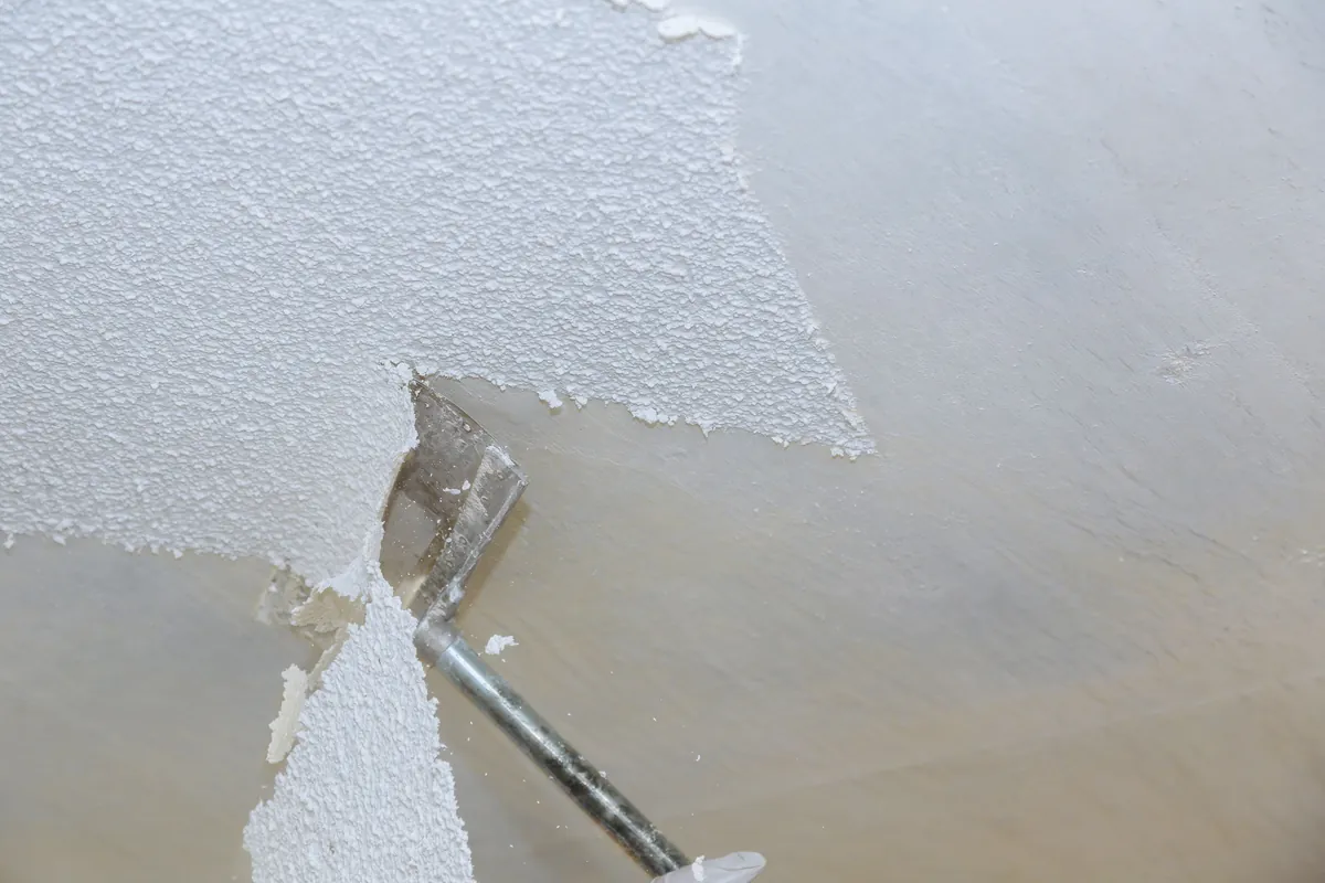 Ceiling part way through removal, the old texture still in place on one side.