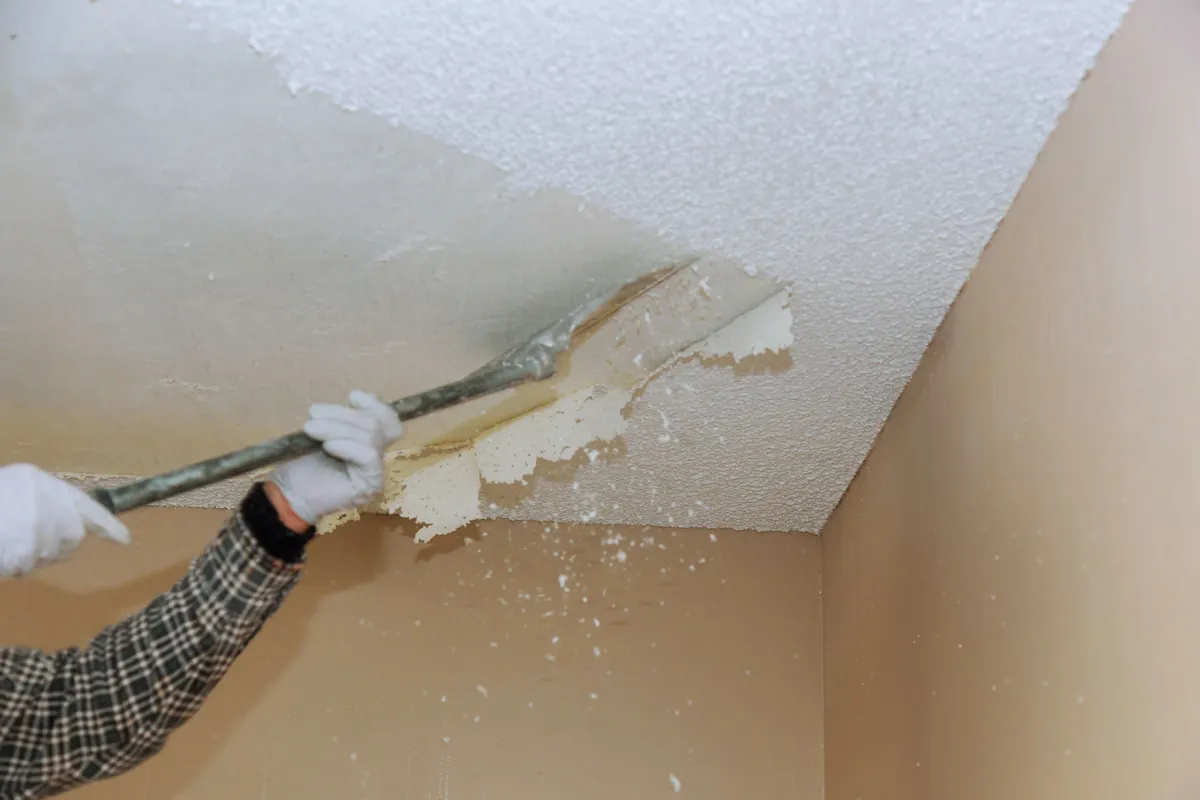 Scraper taking a textured ceiling back to a flat surface ready for finishing.