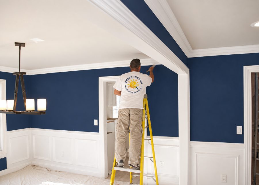 Interior painter cutting a clean edge along ceiling trim in a South Florida living room