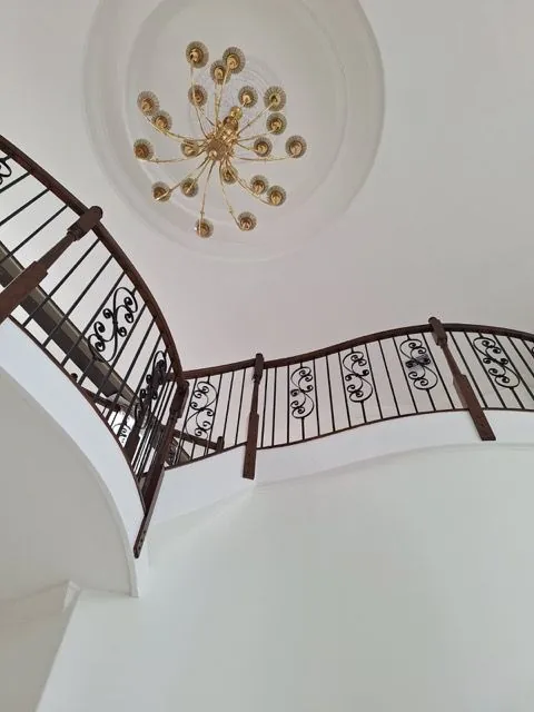 Domed ceiling with a chandelier seen from below, beside the curved landing rail.